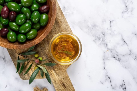 Chalkidiki olives, classic Greek green olives, in a bowl on a cutting board, top view, without