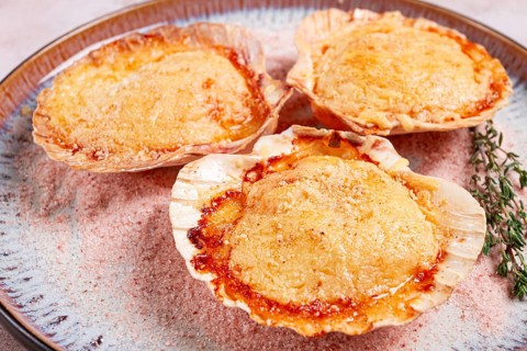 Scallop, baked in shells, with cheese and spices, on a plate, homemade