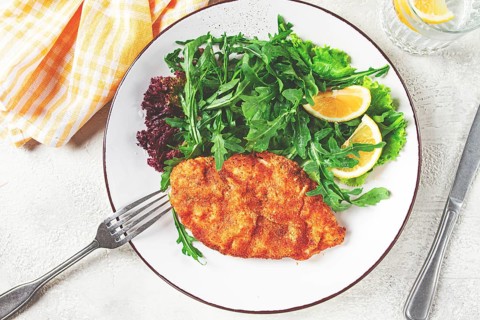 Milanese chicken, Crispy breaded chicken served, with fresh herbs, and lemon wedges
