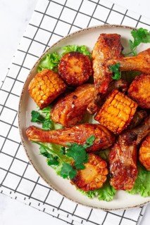 Fried chicken drumsticks, Mexican style, with corn, on a plate, close-up