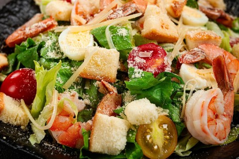 Caesar salad with tiger prawns, shrimp salad, lettuce leaves, quail eggs, cherry tomatoes, parmesan