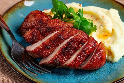 Roast duck breast, sliced with mashed potatoes, on a plate, close-up, no people