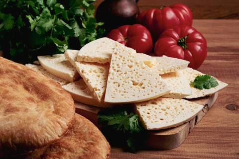 Georgian sliced cheese, on a wooden chopping board, with tomatoes with herbs and lavash, rustic