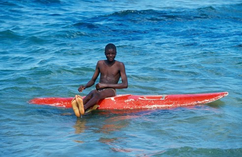 Teenager sitting on a surfboard in Lake Malawi, Kande, Malawi, Africa, July 2000, vintage, retro,
