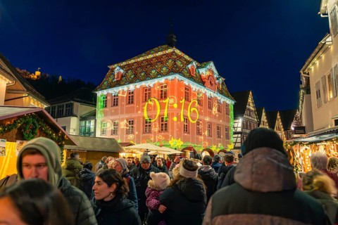 Illuminated building projection showing time at a well-visited Christmas market, Christmas market