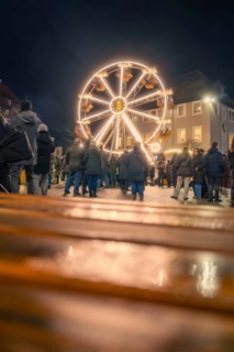 People come together to enjoy an illuminated Ferris wheel at night, Christmas market 2025, Nagold,