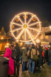 People gather in a Christmas square in front of an illuminated Ferris wheel, Christmas market 2025,