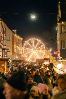 Busy Christmas market at night with illuminated Ferris wheel in the background, Christmas market