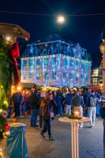Illuminated building with Christmas projections in front of numerous market visitors, Christmas