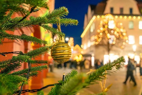 Golden Christmas ball on a pine branch with blurred city lighting in the background, Christmas