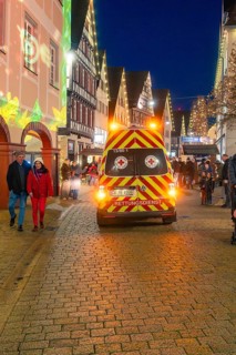Night view of an emergency service vehicle at a busy and festive Christmas market, Christmas market