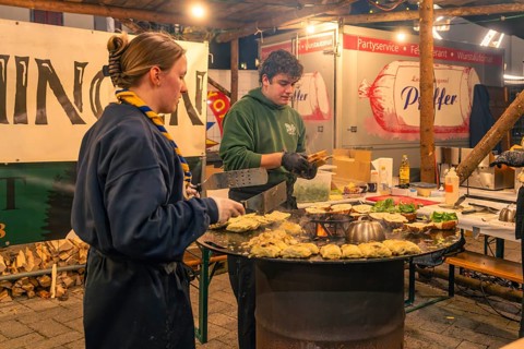 Active chefs prepare food at a stand at a Christmas market, Christmas market 2025, Nagold, Black