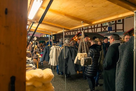 People browse through a range of textiles at a nightly Christmas market, Christmas market 2025,