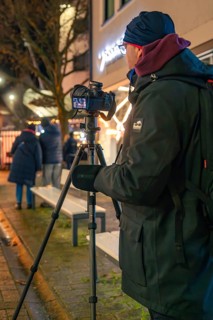 A photographer sets up his camera on the street at night, Christmas market 2025, Nagold, Black