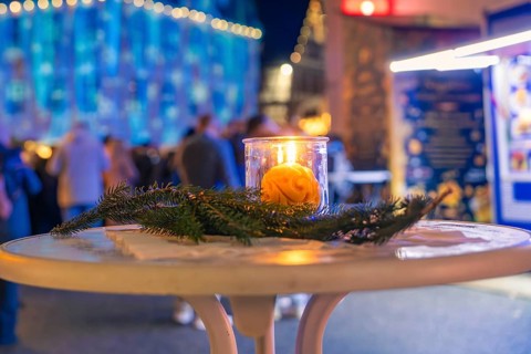 A burning candle on a decorated table at night at a Christmas market, Christmas market 2025,