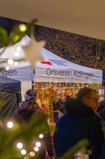 Visitors stroll past a tent that is lit up for Christmas, Aidlingen Christmas Market, Böblingen