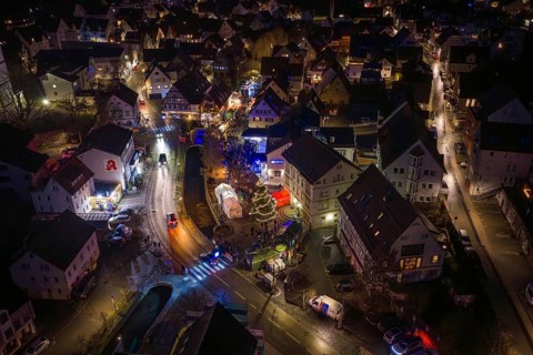 Night view of a Christmas market with glowing lights, roads and decorated Christmas tree, Aidlingen