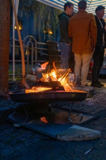 A few people stand next to a warming fireplace at night, Aidlingen Christmas market, Böblingen