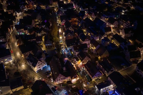 Festively illuminated village at night with lots of people and lights, Aidlingen Christmas market,