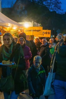 Crowd of people wait in front of an illuminated food stand at night, Aidlingen Christmas market,