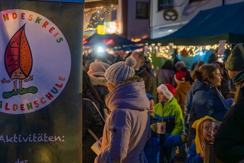 Visitors stroll through a brightly lit and festively decorated Christmas market with children,