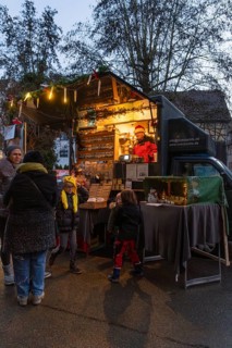 An illuminated food truck at a street market with people in a nocturnal atmosphere, Aidlingen