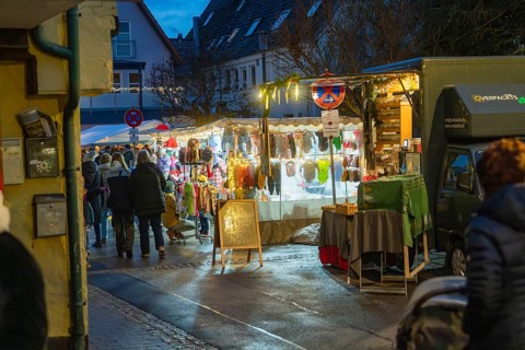 Night market with illuminated stalls and people in cold weather, Aidlingen Christmas market,