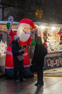 Two woman talking in front of an inflatable Santa Claus and an illuminated stand, Aidlingen