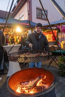 Man grilling chestnuts at a Christmas market in a pleasant evening mood, Aidlingen Christmas