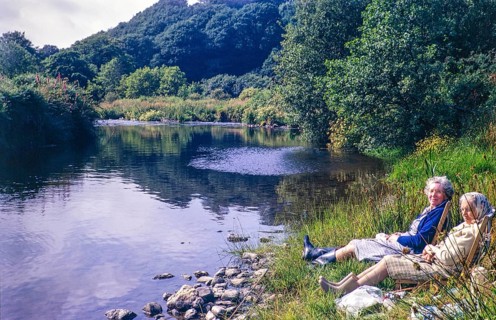 Two women sitting in deckchairs by the side of River Nevern, Penwaun, Nevern, Pembrokeshire, Wales,
