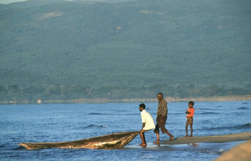 Men letting dugout into water, boy, Lake Malawi, Kande, Malawi, Africa, July 2000, vintage, retro,