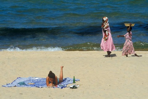 Tourist in bikini and traditionally dressed local woman at Kande Beach on Lake Malawi, Malawi,