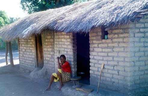 Woman sitting in front of a house in a village near Kande on Lake Malawi, Malawi, Africa, July
