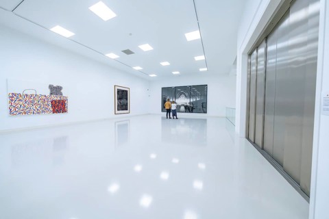 Two people look at works of art in a modern, bright exhibition room, Open Horizons exhibition,