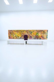Large, colorful, abstract work of art in minimalist space with bench in front of it, Open Horizons