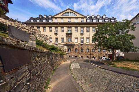 Sandstone wall, historic building, house, faÃ§ade with windows, dormers, asphalt sidewalk,