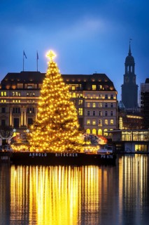 The decorated and illuminated Alster fir tree on the Inner Alster with reflections on the water in