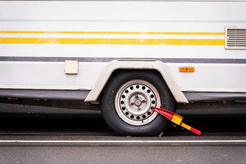 Caravan wheel with yellow-red parking claw parked on a street, Wuppertal, Germany