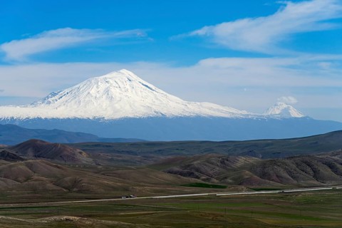 Snow-capped mountains under clear blue sky with vast landscape in the foreground, large and small