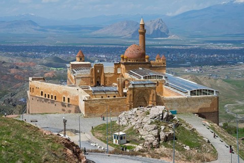 A well-preserved castle in a picturesque mountainous landscape with a partly cloudy sky, Ishak