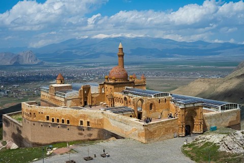 An imposing historic fortress in a mountainous landscape under blue sky with clouds, Ishak Pasha