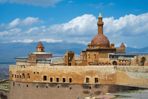 A historic building with dome and minaret, snow-capped mountains in the background, Ishak Pasha