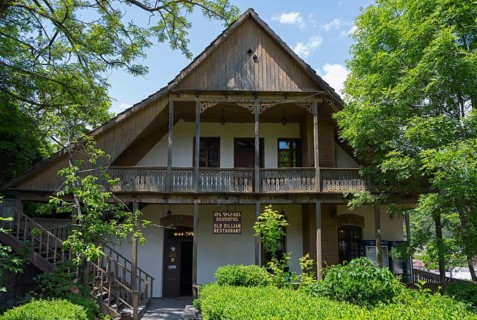 Traditional wooden house with veranda surrounded by green trees and natural ambiance, Old Town,