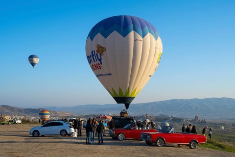People and cars gather around a large balloon ready to launch, hot air balloons, Göreme National