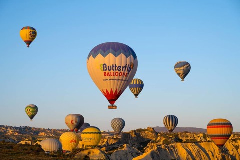 Many colorful hot air balloons rise over rocks early in the morning, Göreme National Park, Göreme