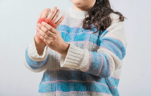 Closeup of woman with arthritis rubbing hands. Unhappy female suffering with pain hands isolated