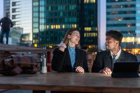 Diverse business colleagues having an outdoor conversation at dusk, sitting at a table in a modern