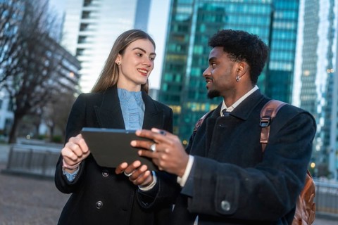 Two diverse business professionals collaborating during an outdoor meeting, sharing ideas and