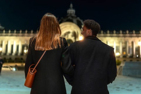 Two women holding arms, enjoying an evening stroll together while exploring the illuminated city