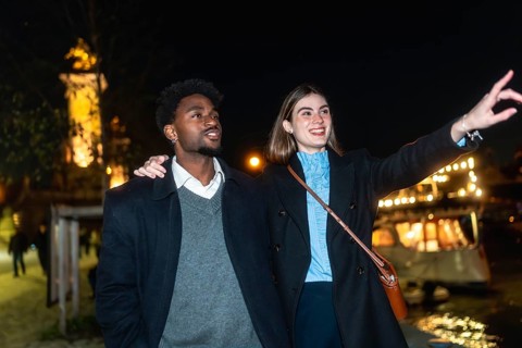 Young couple enjoying a romantic night out, with a woman pointing towards the city lights and a man